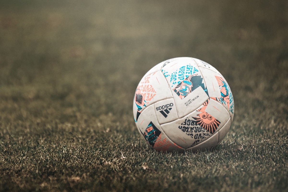 A worn leather soccer ball resting on green turf