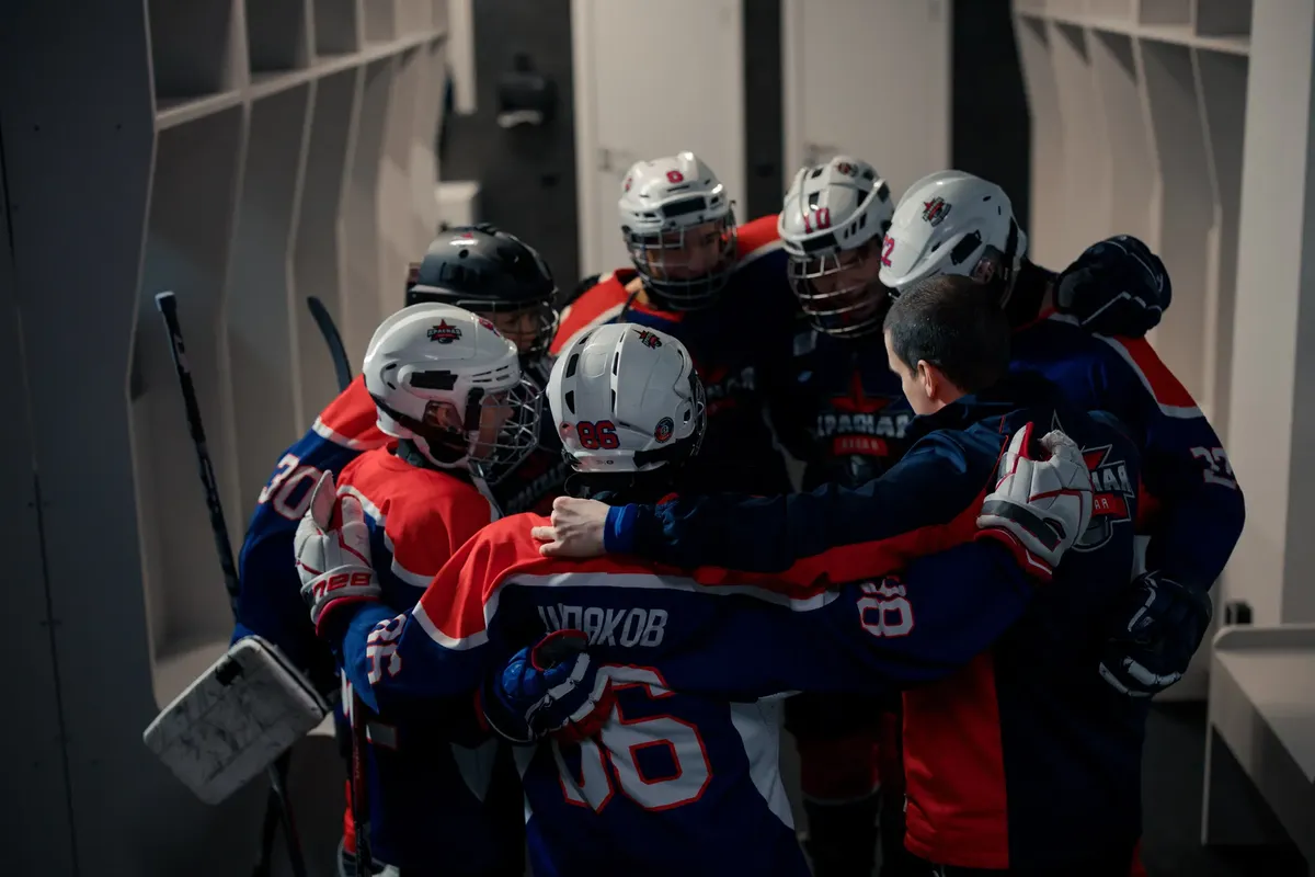 Team of young hockey players in locker room huddle, building team spirit before game.