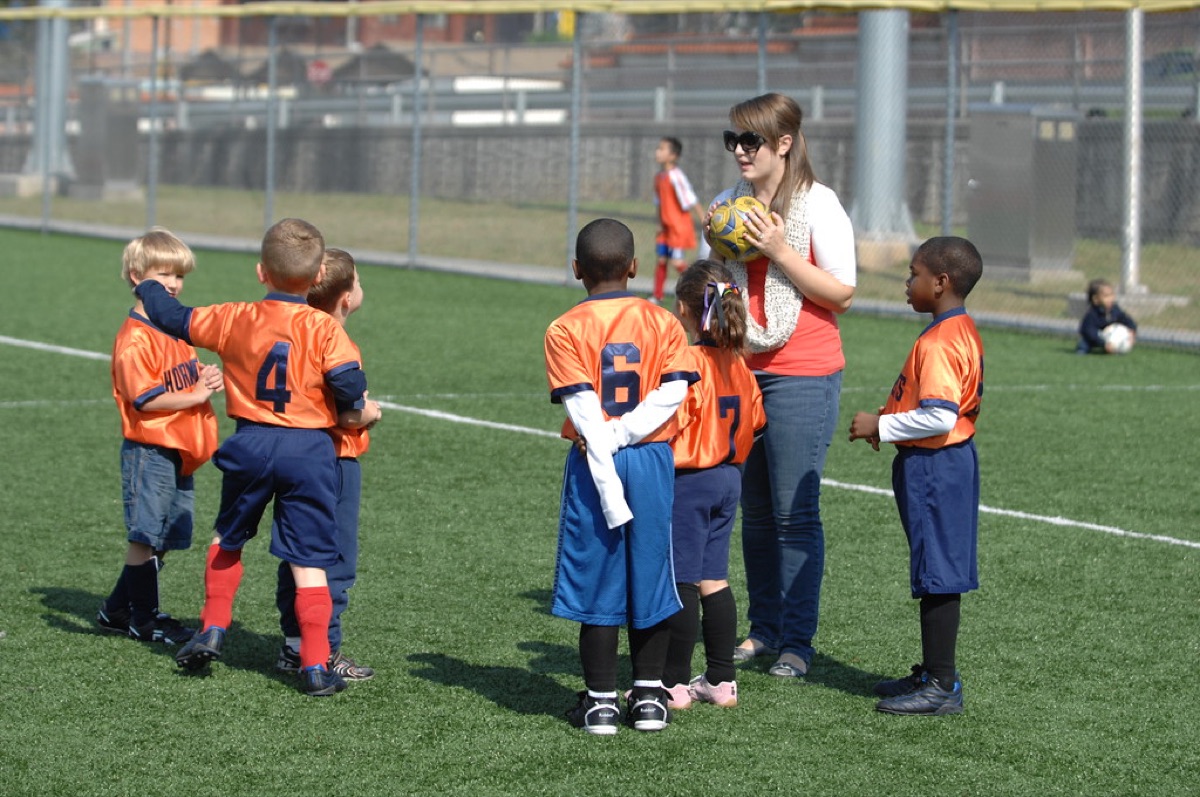 soccer coach and team on field analyzing strategy
