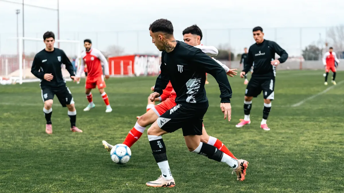 Dynamic soccer match with players in black and red jerseys engaged in a game on a green field.