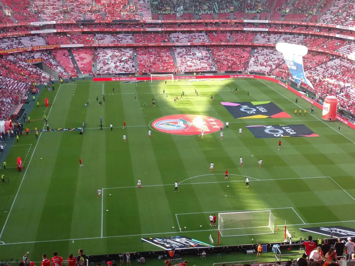 Aerial view of a soccer field during a match in a packed stadium with players and fans.