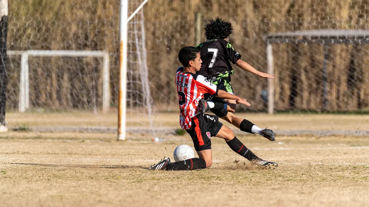 Action-packed moment during a youth soccer game with two players in a competitive tackle.