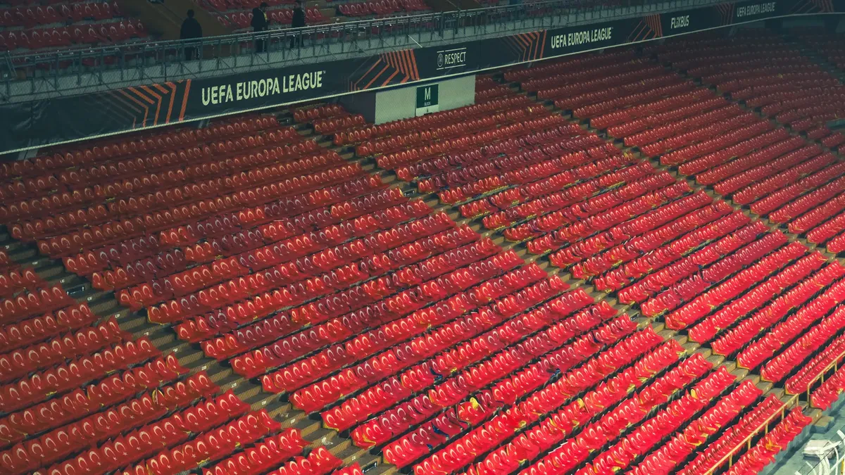 Empty red stadium seats at UEFA Europa League venue, providing spacious copyspace.